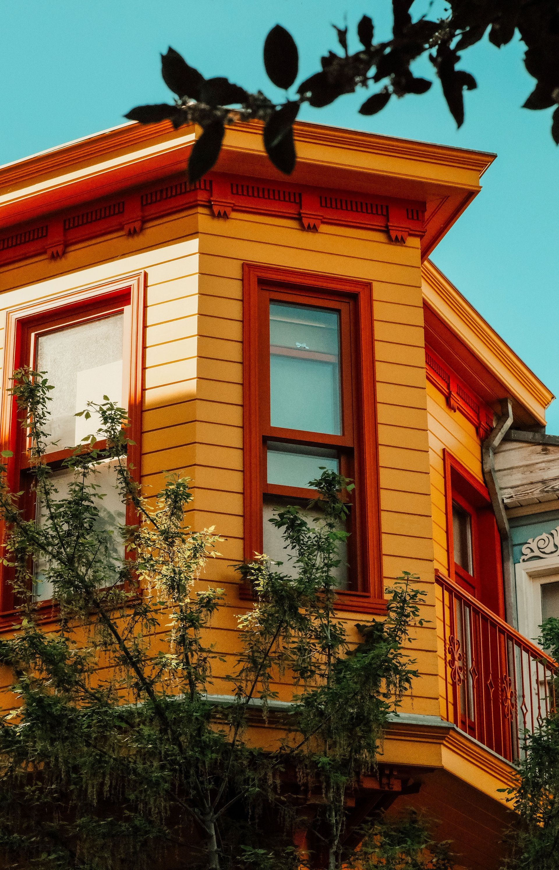 Colorful residential building facade with vibrant yellow paint and balcony, set against a clear sky in İstanbul.