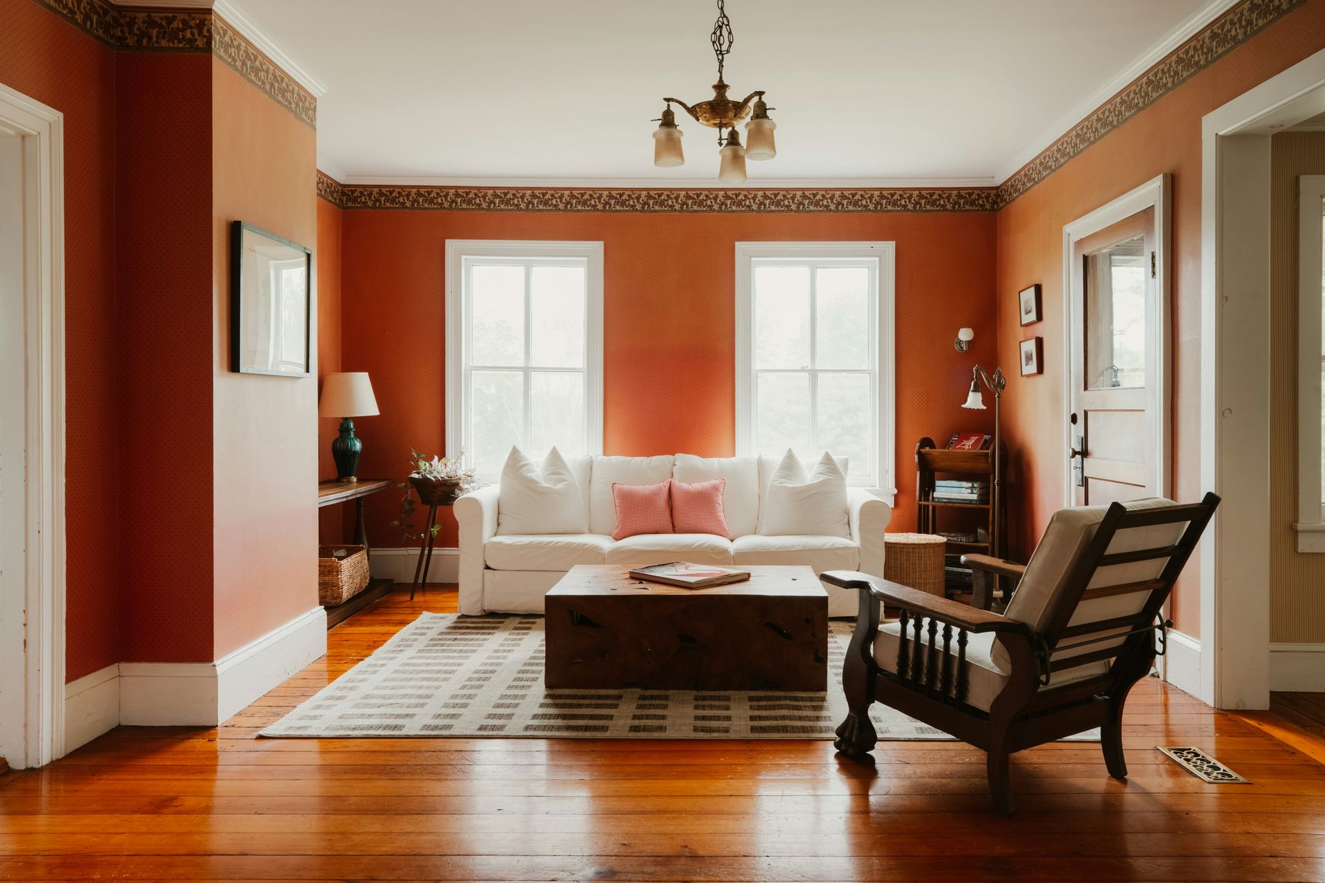 Orange-walled living room with white sofa, wooden table.